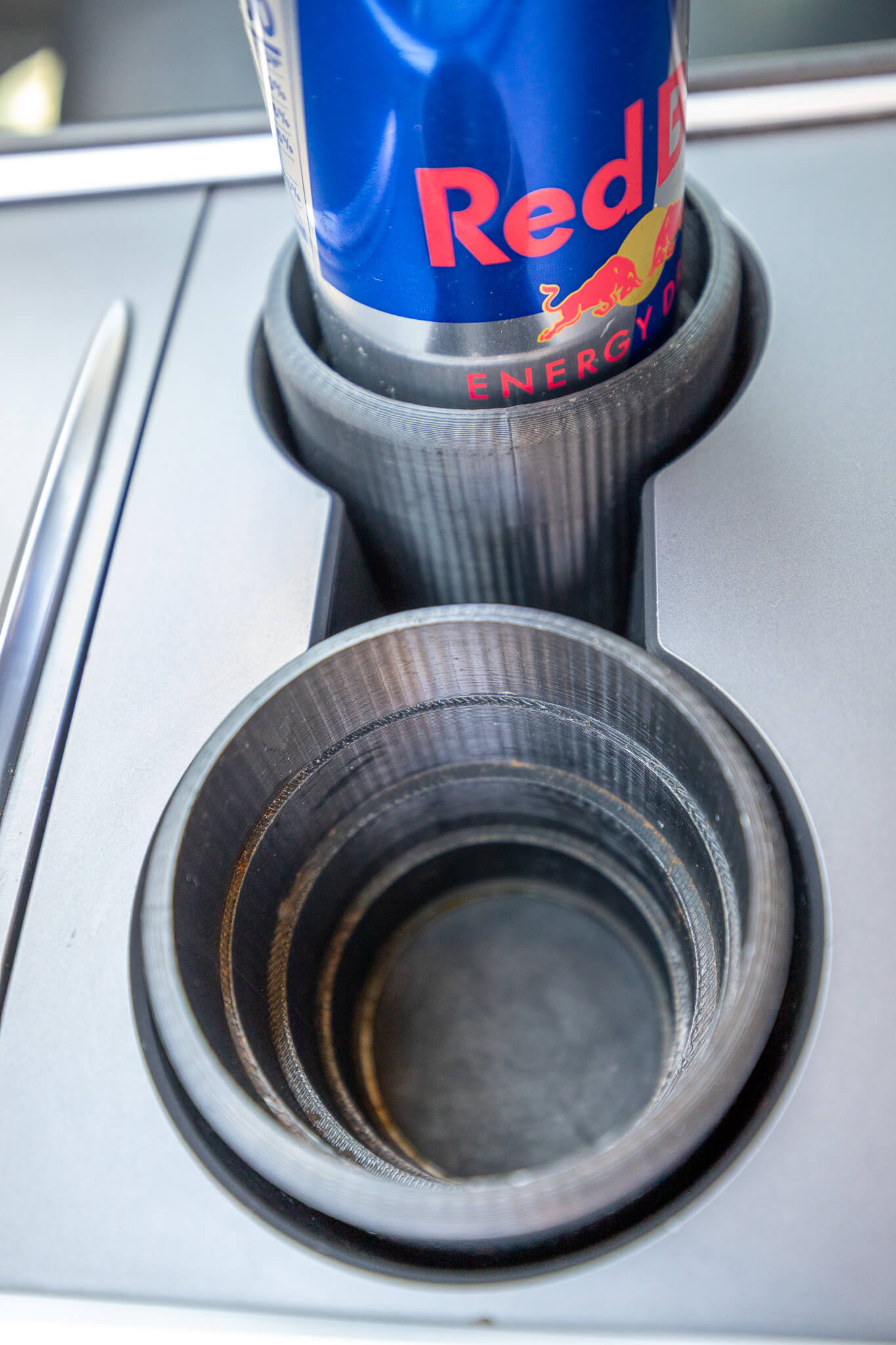 Red Bull can placed in black skinny can holder for cars